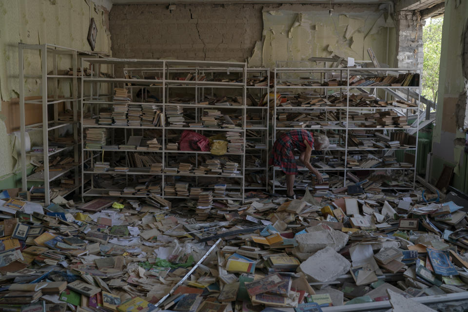 The librarian Raisa Krupchenko, 81, makes a pile of books as she tries to organize them among debris at the library of the destroyed School Number 23 after a Russian attack that occurred in the second half of July, in Kramatorsk, Ukraine, Saturday, Aug. 27, 2022. Krupchenko works on what remains from the school's library looking for textbooks that will be given to the children who remained in Kramatorsk for the beginning of the classes. "I think literature moves the world. American, Ukrainian and Russian, I think it (books/literature) is necessary", she completes. (AP Photo/Leo Correa)