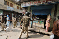 Indian security officers order a shop to be shut in New Delhi, India, Wednesday, Feb. 26, 2020. At least 20 people were killed in three days of clashes in New Delhi, with the death toll expected to rise as hospitals were overflowed with dozens of injured people, authorities said Wednesday. The clashes between Hindu mobs and Muslims protesting a contentious new citizenship law that fast-tracks naturalization for foreign-born religious minorities of all major faiths in South Asia except Islam escalated Tuesday. (AP Photo/Rajesh Kumar Singh)
