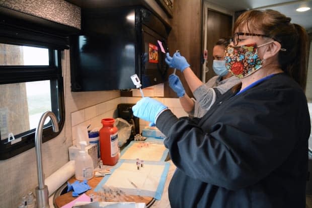 Roberta Wagner, foreground, a health clinic administrator for the Blackfeet Tribe, prepares COVID-19 vaccine doses to be administered to Canadian residents on April 29, 2021. 