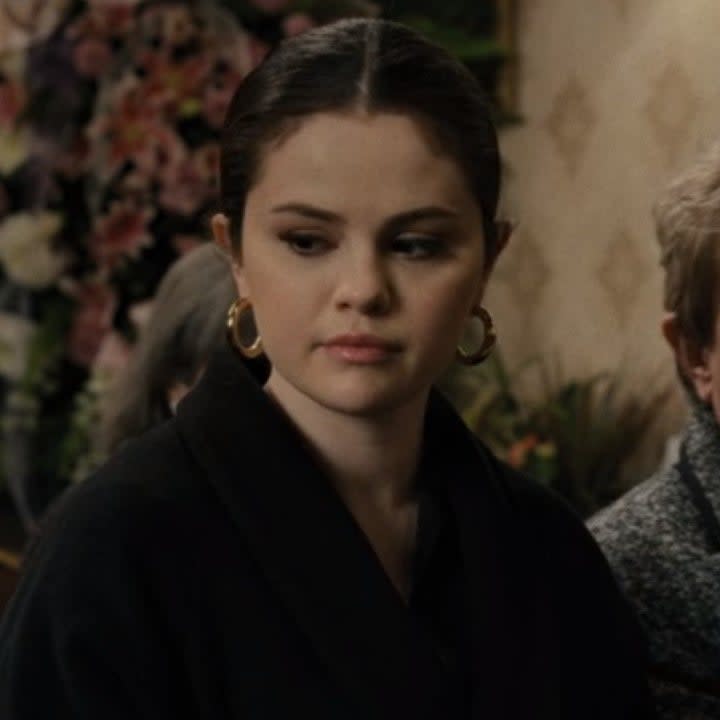 Photo of Selena Gomez as Mabel in a black coat and pink lipstick