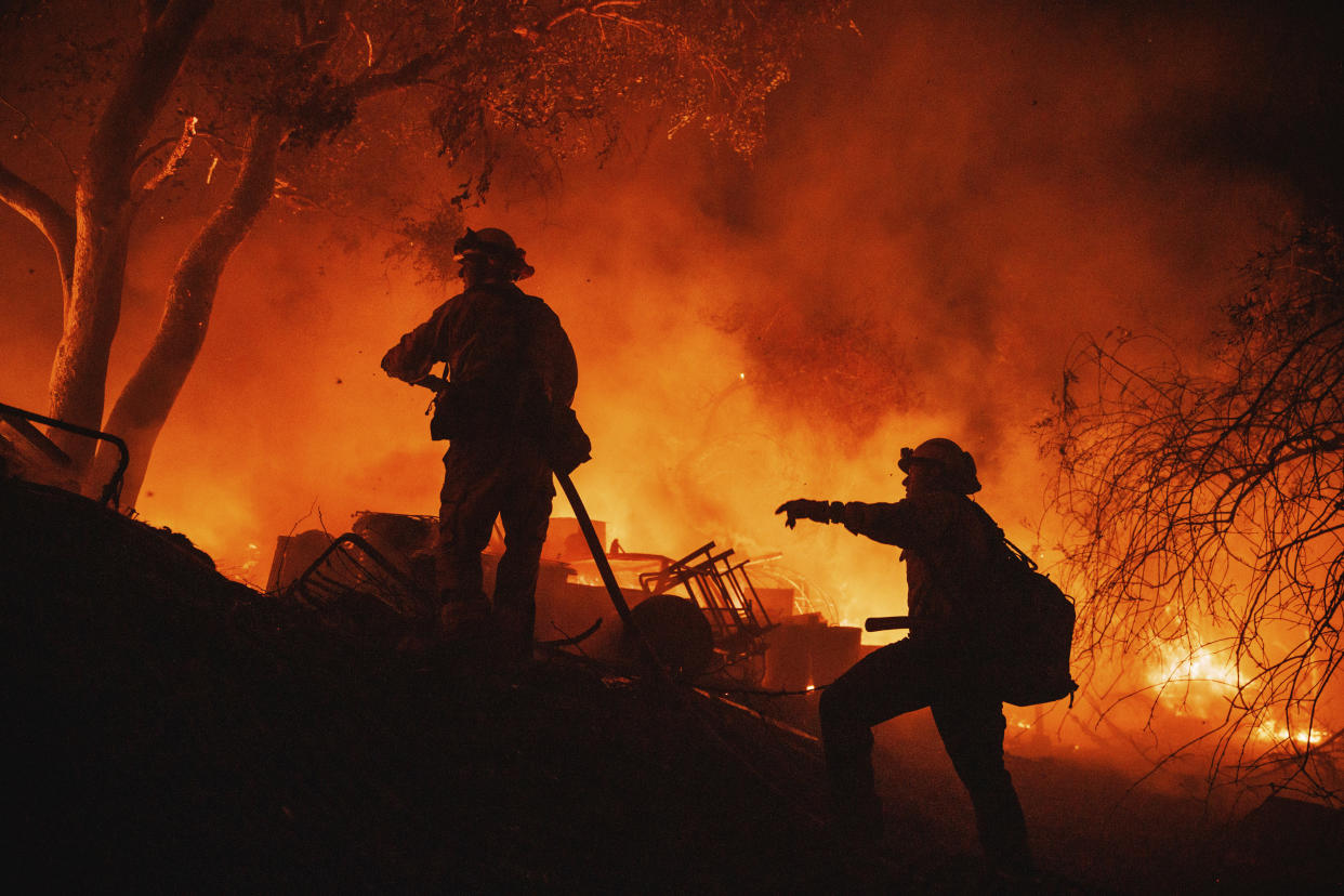 Firefighters coordinate efforts at a burning property while battling the Fairview Fire Monday, Sept. 5, 2022, near Hemet, Calif. (AP Photo/Ethan Swope)