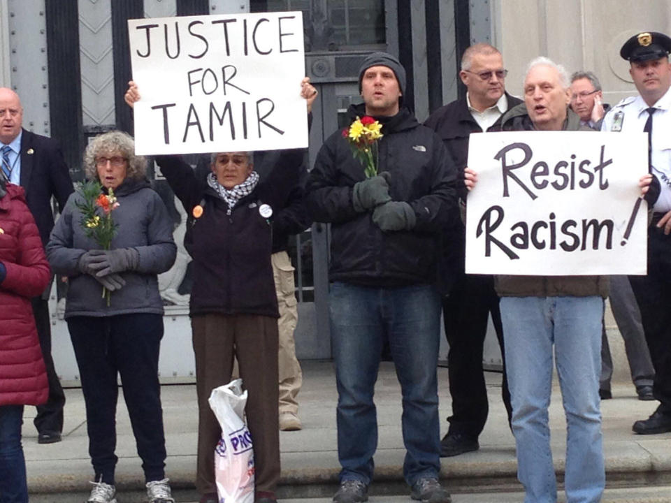 In this 2016 photo, Martin Gugino, right, holds a sign reading "Resist Racism," in Washington, D.C., as part of a protest over the 2014 killing of 12 year-old African American Tamir Rice in Cleveland. Gugino and others demanded murder charges against police officers for the killing. (Mark Colville via AP)