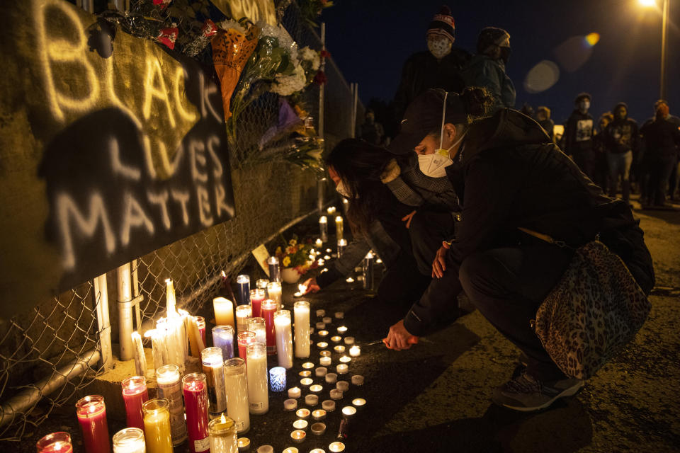 A woman lights a candle as people gather for Kevin Peterson Jr., who was killed in Thursday's shooting with police involved, at a candlelight vigil in Vancouver, Wash., Friday, Oct. 30, 2020. The Clark County Sheriff's office has not released any details on the Thursday evening shooting in Hazel Dell, but a man told The Oregonian/OregonLive that his 21-year-old son was fatally shot by police. (AP Photo/Paula Bronstein)