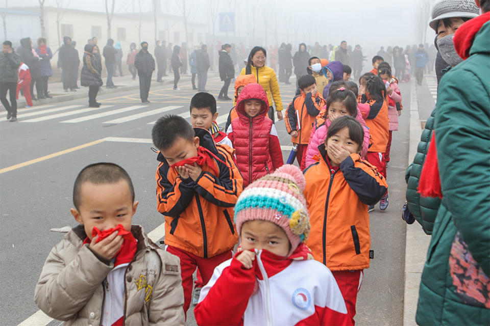 趙亞楠指幼兒園幾乎每天都能聽到孩子啞著嗓子向老師請病假。圖為山東省濱州市，孩子在霧霾下掩著口鼻。
