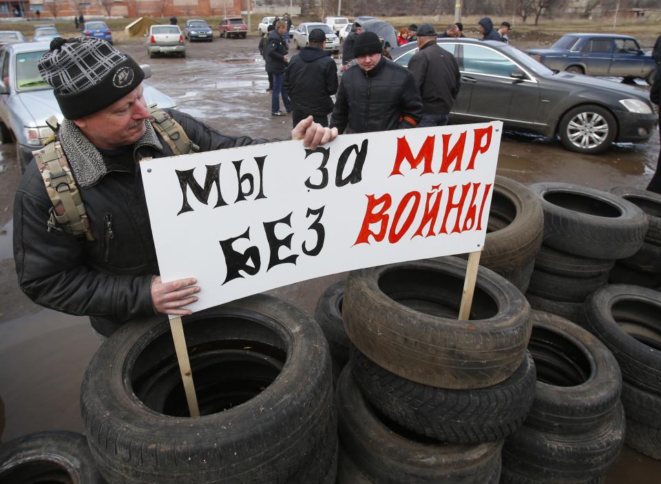 Pro Russian activists install a placard reading "We are for peace without wars" in their camp near the armory of Ukrainian army in the village of Poraskoveyevka, eastern Ukraine, Thursday, March 20, 2014. The disheveled men barricading the muddy lane leading into a military base in this eastern Ukraine village say they're taking a stand to defend Russian-speakers. (AP Photo/Sergei Grits)