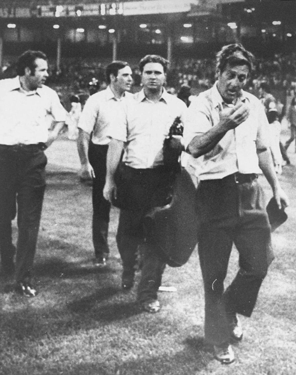 FILE - In this image provided by Special Collections, Cleveland State University, injured umpire Nestor Chylak, right, leads his crew, from left, Joe Brinkman, Nick Bremigan, and Larry McCoy off the field during the Beer Night melee at Cleveland Stadium, June 4, 1974, in Cleveland. The Cleveland Indians forfeited the baseball game to the Rangers after fans, fueled by 10-cent beers, stormed the field in the ninth inning. (Paul Tepley/Cleveland Press, Special Collections, Cleveland State University, via AP, File)