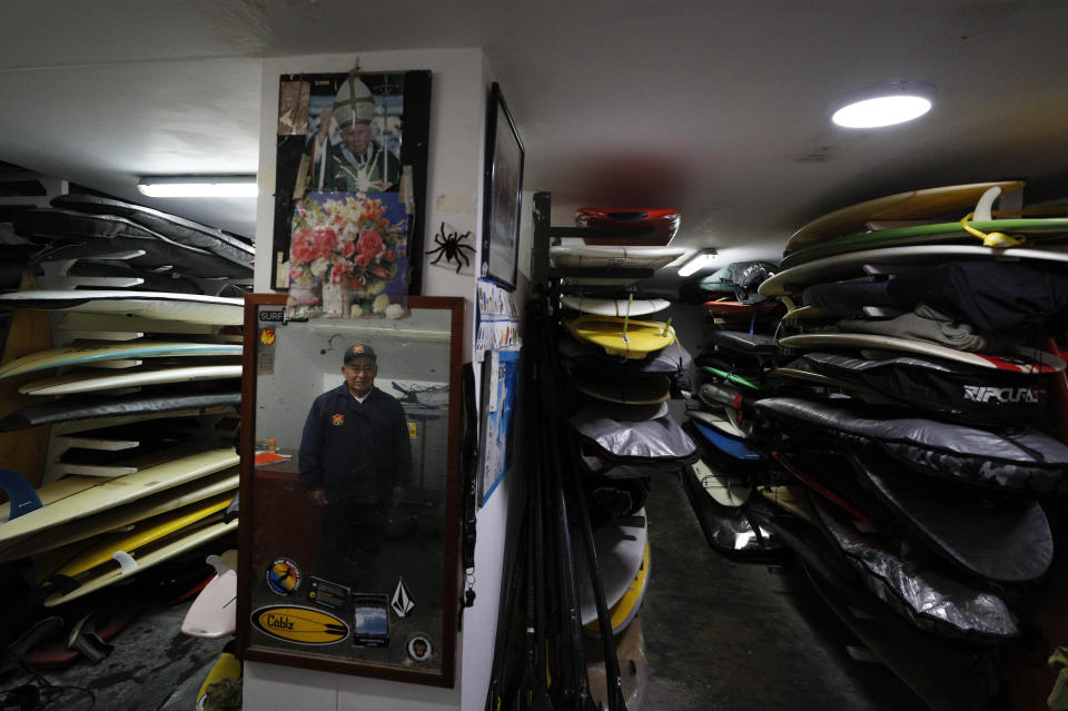 In this July 26, 2019 photo, Victor "Mamico" Curo, 79, stands amidst the thousands of surfboards he tends in the storage room named after him for his more than 60 years of service, at Club Waikiki in Lima, Peru. Surfing is a way of life in Peru, which has been called the Hawaii of Latin America.(AP Photo/Rebecca Blackwell)