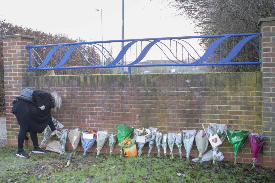 A woman lays flowers at the entrance to Debden Park High School, in Loughton, Essex, as a murder investigation has been launched after a 12-year-old boy was killed when a car crashed into children.