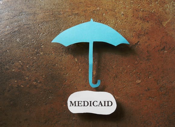 A paper umbrella above a piece of paper with Medicaid written on it.