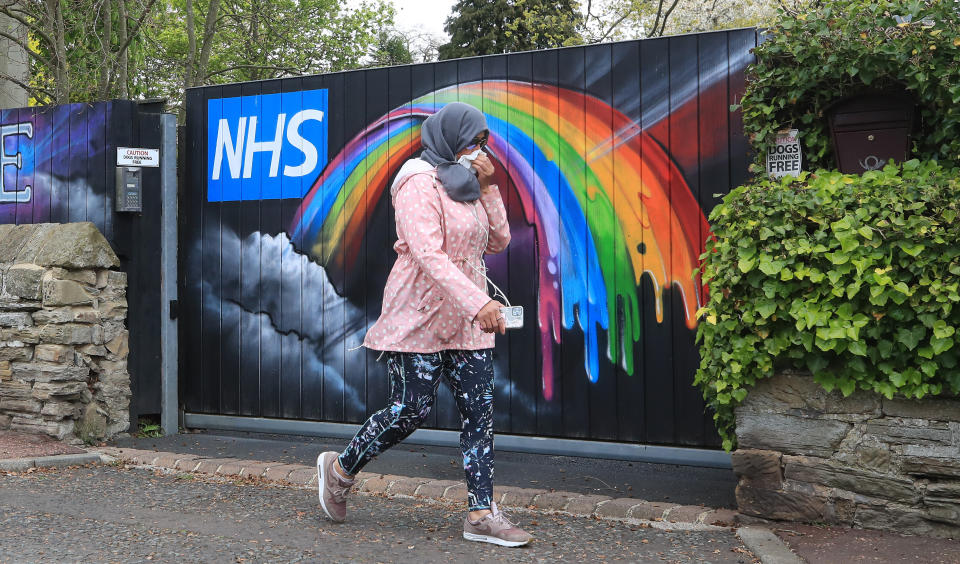 A woman walks past rainbow NHS graffiti on one of the gates to a mansion in Woolsingham in Newcastle as the UK continues in lockdown to help curb the spread of the coronavirus.