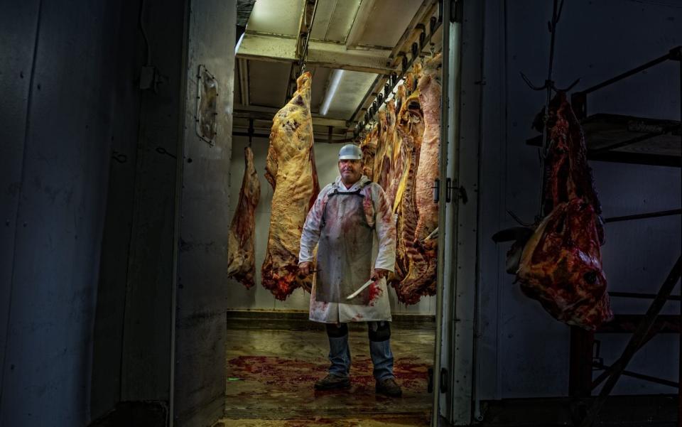 A butcher stands in his meat locker - Getty