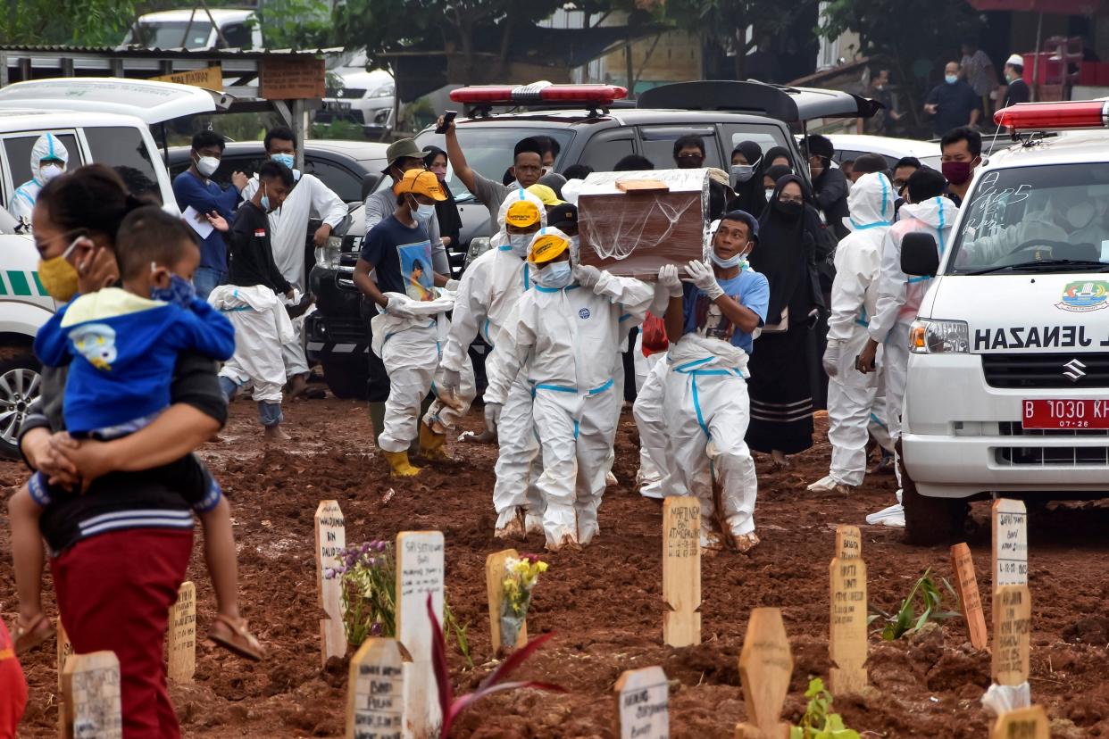 Funeral workers prepare to bury deceased Covid-19 coronavirus victims who were brought by ambulance directly from hospitals, at the Pedurenan public cemetery in Bekasi, West Java on 23 July 2021 (AFP via Getty Images)