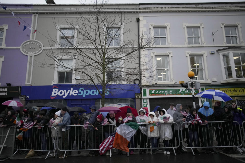 People line the streets holding flags and banners in heavy rain as they wait for President Joe Biden to arrive for events in Dundalk, Ireland, Wednesday, April 12, 2023. President Biden is three day visit to Ireland. (AP Photo/Christophe Ena)