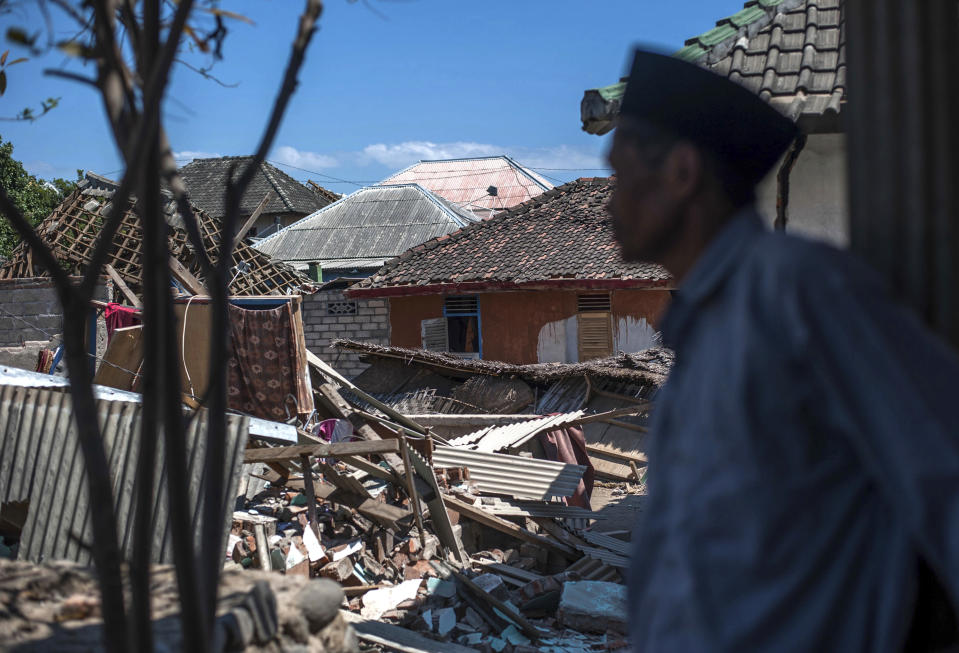 An Indonesian man inspects the damage in a village from a major earthquake in Kayangan on Lombok Island, Indonesia, Monday, Aug. 6, 2018. Indonesian authorities said Monday that rescuers still haven't reached some devastated parts of the tourist island of Lombok after the powerful earthquake flattened houses and toppled bridges, killing large number of people and shaking neighboring Bali. (AP Photo/Fauzy Chaniago)