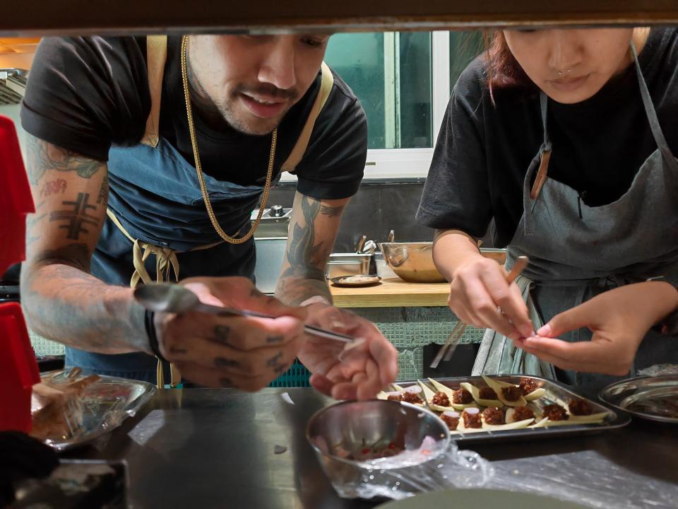 Dylan Eitharong preparing food with another chef at Haawm