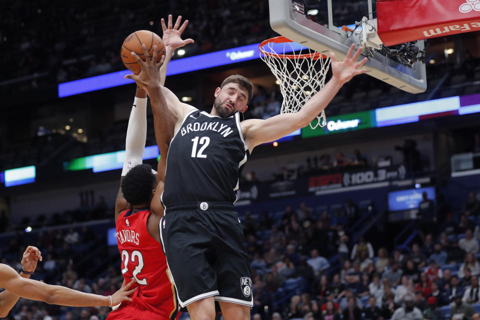 Brooklyn Nets guard Joe Harris (12) fouls New Orleans Pelicans forward Derrick Favors (22) as he goes to the basket in the first half of an NBA basketball game in New Orleans, Tuesday, Dec. 17, 2019. (AP Photo/Gerald Herbert)