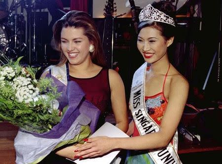 Alicia Machado of Venezuela (L), the reigning Miss Universe, poses with the winner of the Miss Singapore/Universe paegent, Tricia Tan, after being presented with a bouquet of flowers March 15. REUTERS/Files