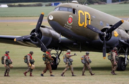 Paratroopers in World War II uniforms walk to their Dakota aircraft prior to take-off from Duxford airfield as they head to Normandy in France