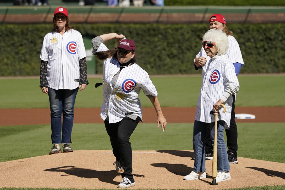 Actress Tracy Reiner, center, who played Betty "Spaghetti" in the movie "A League Of Their Own", throws out a ceremonial first pitch with Maybelle Blair, right, an original member of the All-American Girls Professional Baseball League, during a 30th anniversary ceremony of the film shot a Wrigley Field, before a baseball game between the Chicago Cubs and the Philadelphia Phillies Thursday, Sept. 29, 2022, in Chicago. (AP Photo/Charles Rex Arbogast)