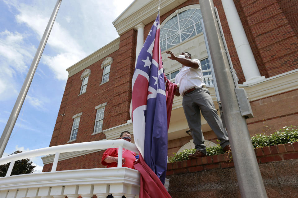 FILE - In this Monday, June 29, 2020, file photo, City of Tupelo Community Outreach Coordinator Marcus Gary takes down the Mississippi state flag that flew over the City Hall of Tupelo one last time Monday, June 29, 2020. Mississippi is retiring the last state flag in the U.S. that includes the Confederate battle emblem. (Thomas Wells/The Northeast Mississippi Daily Journal via AP, File)