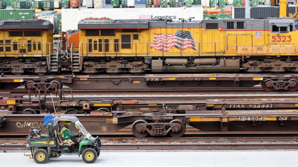 PHOTO: A worker drives near freight trains and shipping containers in a Union Pacific Intermodal Terminal rail yard on Nov. 21, 2022, in Los Angeles. (Mario Tama/Getty Images)