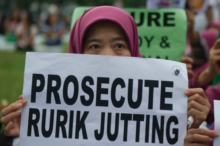 An Indonesian migrant worker holds up a placard during a vigil for slain colleagues Seneng Mujiasih and Sumarti Ningsih in Hong Kong