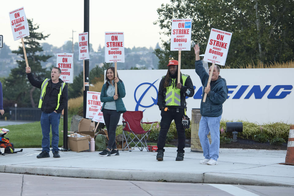 Boeing Machinists Union members from left, Brent Roberts, Ha Nguyen, Myles Simms and Rich Russell, wave to passing traffic while on the picket line at the Renton assembly plant, Friday, Sept. 13, 2024, in Renton, Wash. (AP Photo/John Froschauer)