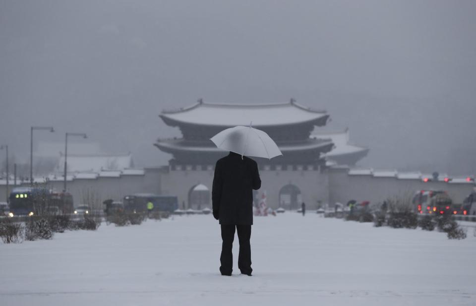 In this Friday, Jan. 20, 2017 photo, a man with an umbrella stands in snow in front of the Gwanghwamun, the main gate of the 14th-century Gyeongbok Palace, one of South Korea's well-known landmarks, in Seoul, South Korea. (AP Photo/Lee Jin-man, File)