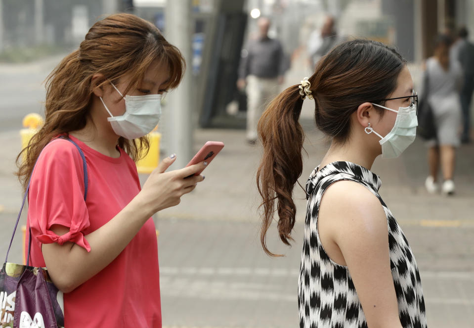 FILE - In this Jan. 2, 2020, file photo, pedestrians wear masks as smoke shrouds the Australian capital of Canberra, Australia. It's an unprecedented dilemma for Australians accustomed to blue skies and sunny days that has raised fears for the long-term health consequences if prolonged exposure to choking smoke becomes the new summer norm. (AP Photo/Mark Baker, File)