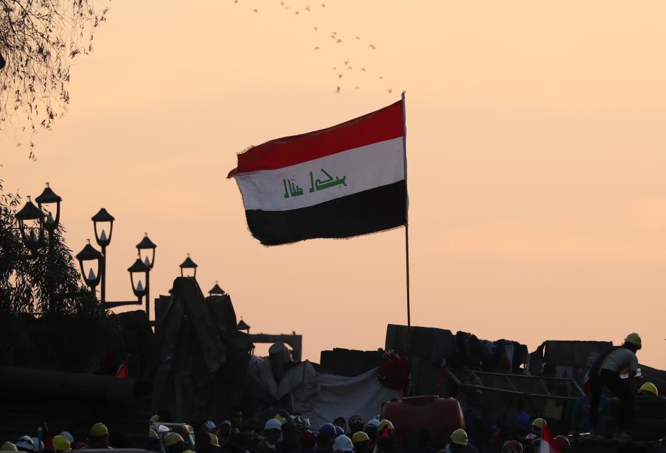 Anti-government protesters stand on barriers set up by Iraqi security forces in an effort to close a bridge leading to the Green Zone government area, during ongoing protests in Baghdad, Iraq, Tuesday, Nov. 5, 2019. (AP Photo/Hadi Mizban)