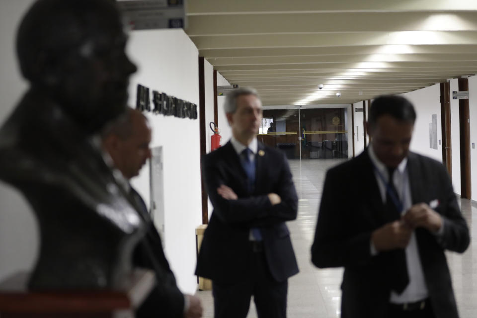 Federal Police stand outside the office, background, of Senator Fernando Bezerra Coelho, the government leader in the Federal Senate, as they agency searches his office in Brasilia, Brazil, Thursday, Sept. 19, 2019. Brazilian police say the governing coalition's leader in the Senate is one of the targets of an investigation into a possible kickback scheme. (AP Photo/Eraldo Peres)