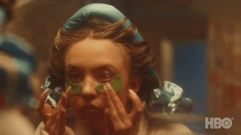 Woman applying facial patches while wearing a shower cap