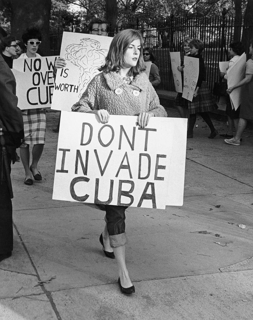 Picture shows people picketing outside of the White House in protest of the US involvement with Cuba. The woman in the foreground is holding a sign plainly stating her point, 'Don't invade Cuba'. Undated photo circa 1960s.