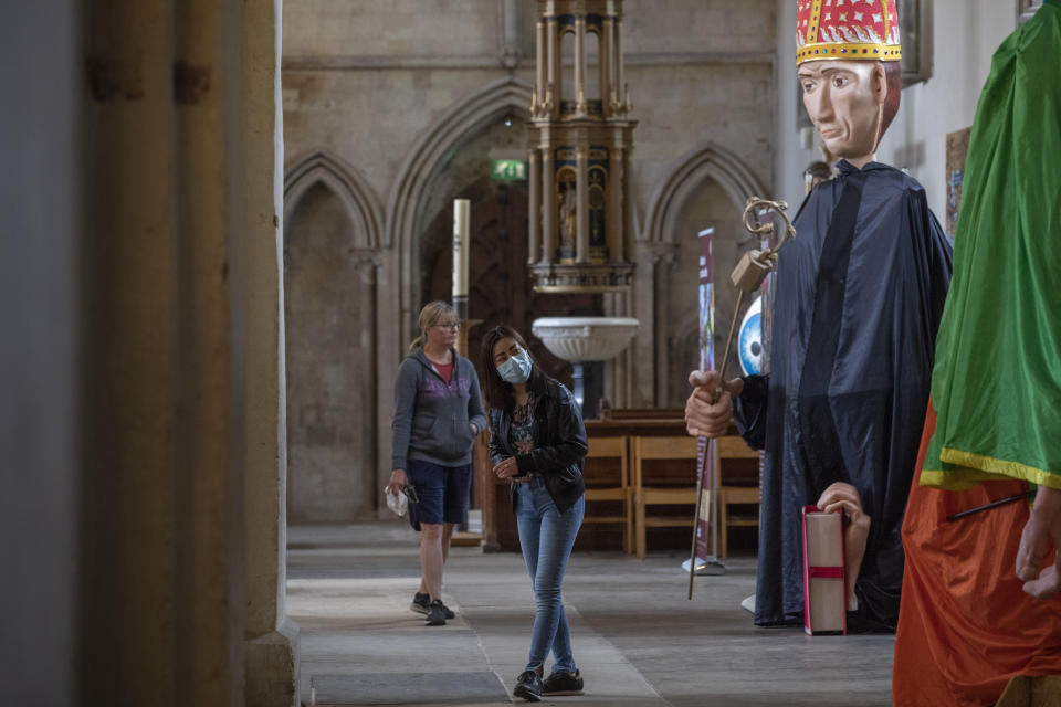 Gente contempla los títeres gigantes, parte de una peregrinación anual que la pandemia obligó a cancelar, en la catedral de St. Albans, Inglaterra, 2 de julio de 2020. (AP Foto/Elizabeth Dalziel)