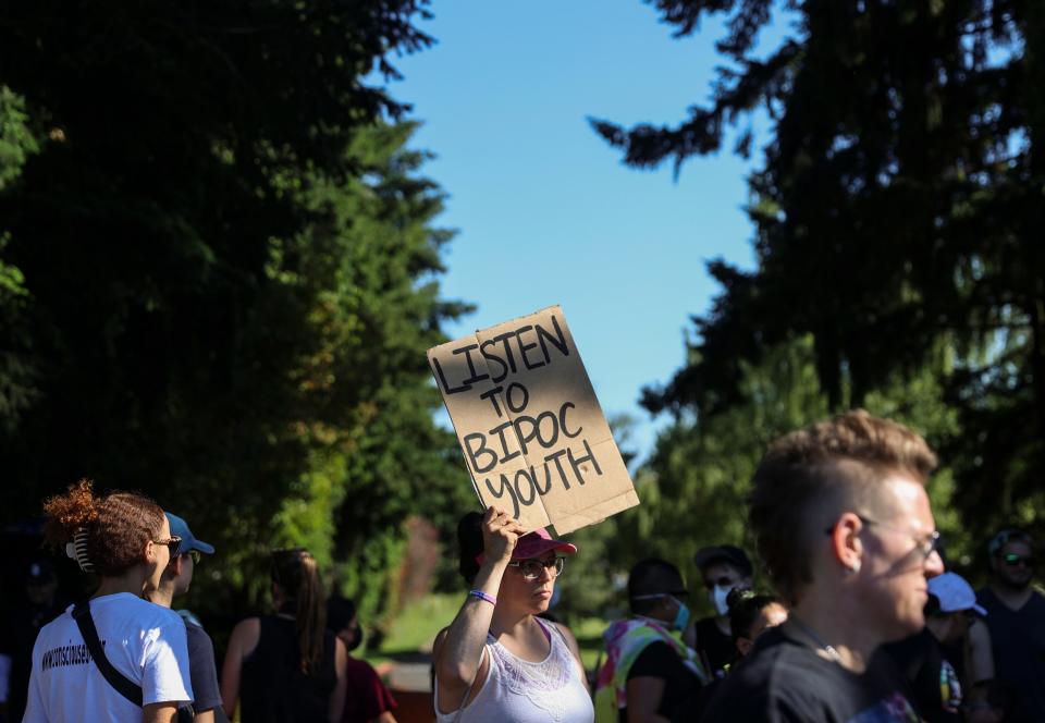 ommunity members and Latinos Unidos Siempre wave signs in front of Robert High School in Salem Thursday.