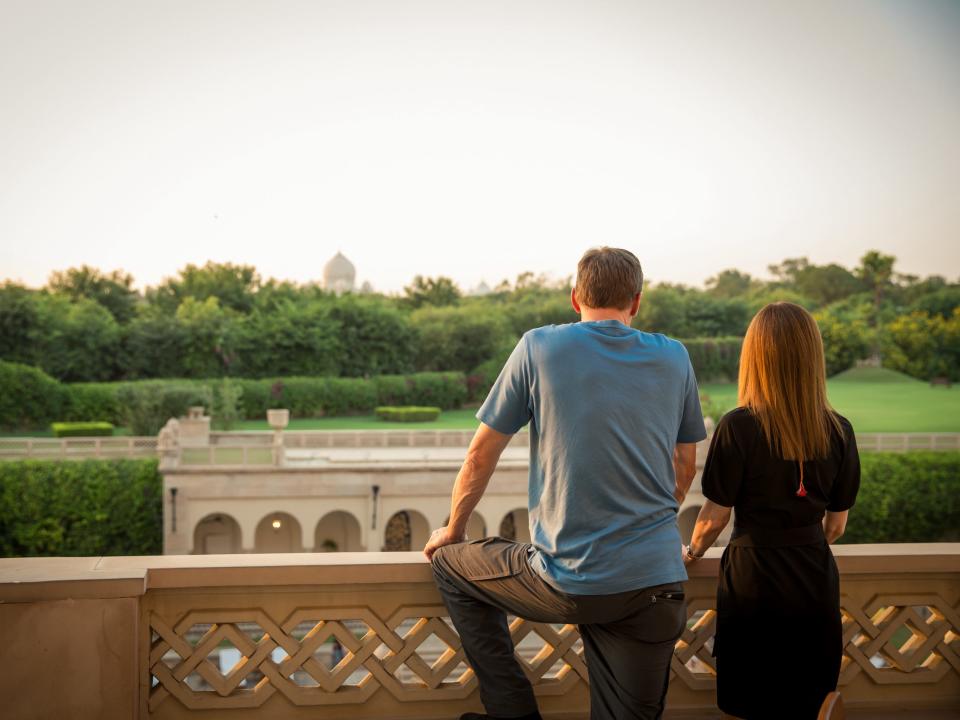 Two people looking at a view of fields, trees, and a monument in the distance.