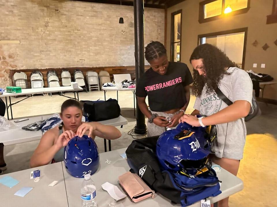 Lady Dukes players Katie Stewart (left), Adayah Wallace and Hannah Davila decorate their new EvoShield helmets from a partnership with Wilson at a team retreat in El Campo, Texas.