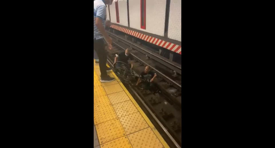 A screenshot of a video showing the dramatic moment man leaped onto the subway tracks to save a man in a wheelchair. Source: Twitter/SubwayCreatures