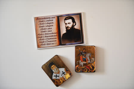 Religious pictures including a portrait of Arsenie Boca, a Romanian Orthodox monk, theologian and artist (top), hang on the wall at the home of Adi and Maria in London, Britain, February 17, 2019. REUTERS/Alecsandra Dragoi