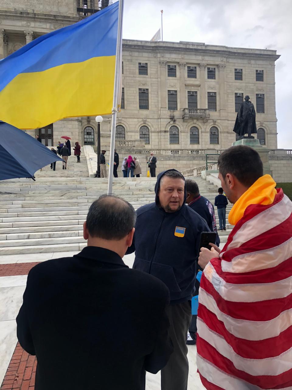 Brothers Oleg Fedorchuk, hoisting the Ukranian flag, and his brother Yevgen, draped in the American flag, attend the rally at the State House to support their native country.