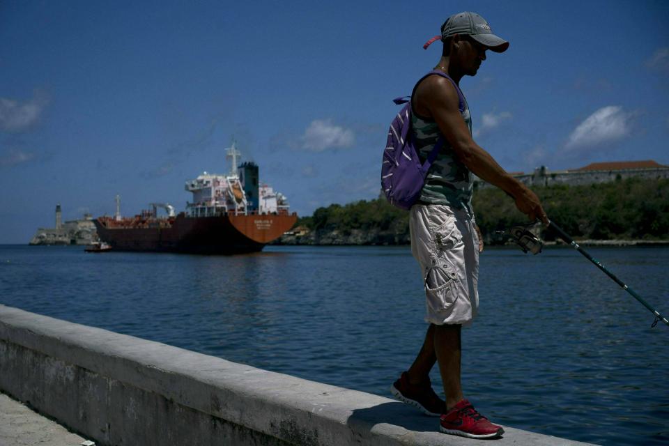 Un pescador camina en el malecón donde se puede ver un barco petrolero en La Habana, Cuba, el miércoles 17 de abril de 2019. (AP Foto / Ramón Espinosa)