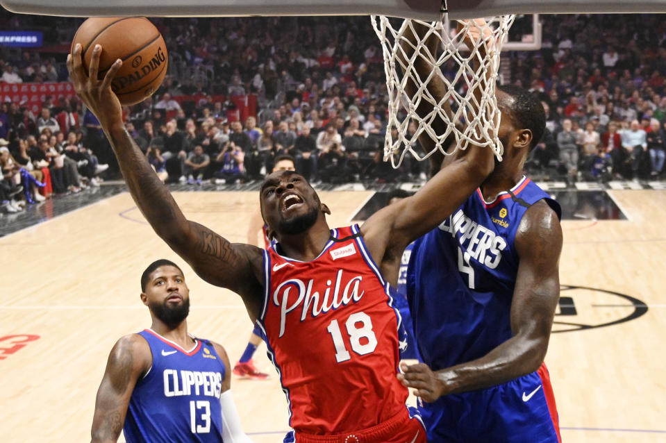 Philadelphia 76ers guard Shake Milton, center, shoots as Los Angeles Clippers forward JaMychal Green, right, defends and guard Paul George watches during the first half of an NBA basketball game Sunday, March 1, 2020, in Los Angeles. (AP Photo/Mark J. Terrill)