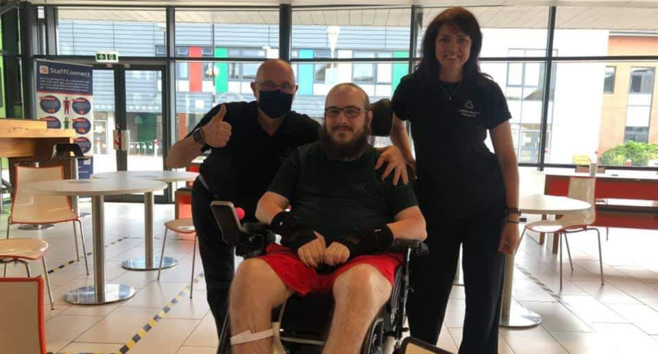 Darren Roberts in his wheelchair with two cafe workers.