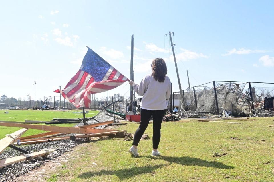 A woman carries an American flag after storms damaged Amory on Friday night.