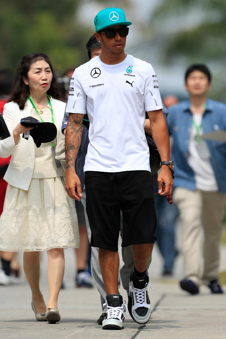 Mercedes driver Lewis Hamilton of Britain walks at the paddock as he arrives for the third practice session and qualifying session for Sunday's Malaysian Formula One Grand Prix at Sepang International Circuit in Sepang, Malaysia, Saturday, March 29, 2014. (AP Photo/Peter Lim)