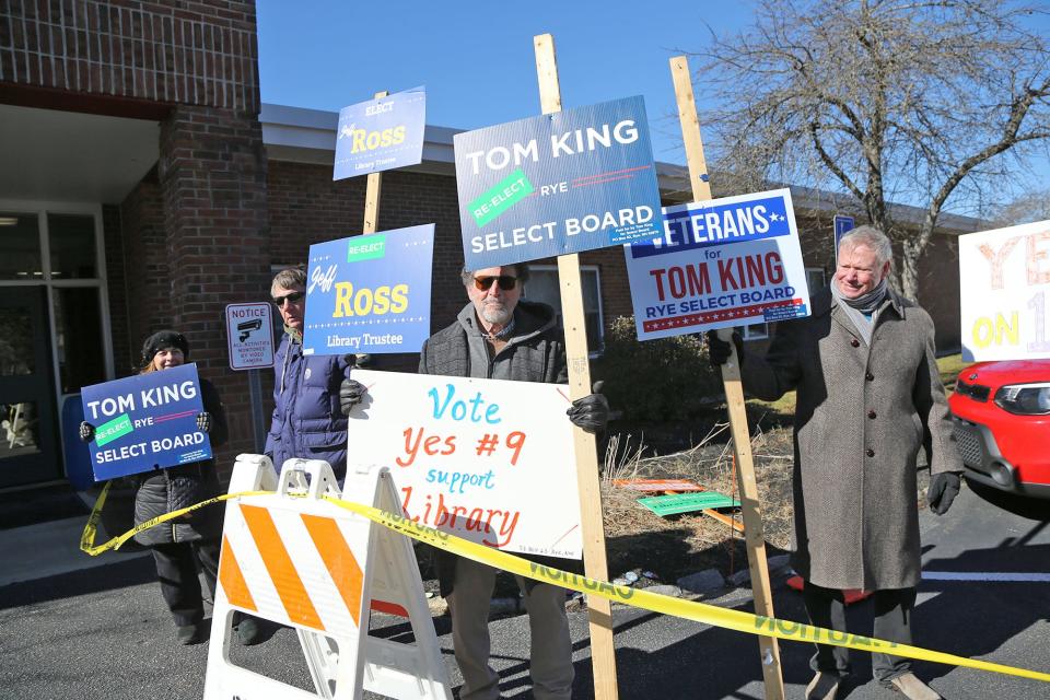 Sign holders greet voters at Rye Elementary School during the town election Tuesday, March 12, 2024.