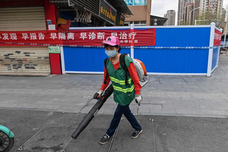 Una mujer con una máscara facial trabaja junto al mercado mayorista de mariscos de Huanan en Wuhan, en la provincia central de Hubei, China, el 30 de marzo de 2020.