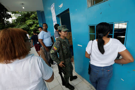 A soldier stands guard as people line up to cast their votes in a school used as a polling station during the presidential election, in Guayaquil, Ecuador April 2, 2017. REUTERS/Henry Romero