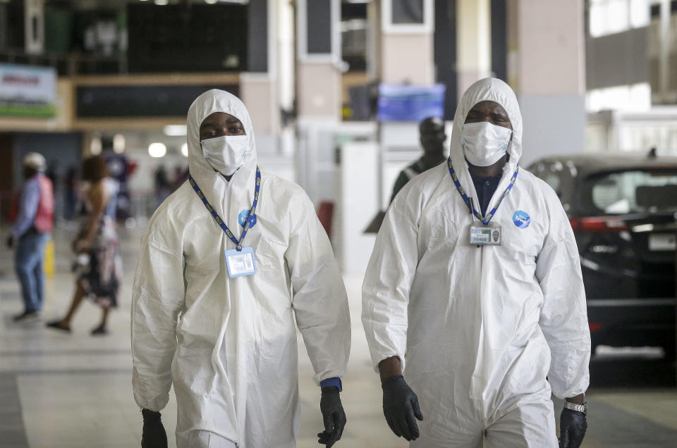 Nigerian aviation workers wear protective clothing as U.S. citizens queue to check in and be repatriated aboard an evacuation flight arranged by the U.S. embassy and chartered with Delta Air Lines, at the Murtala Mohammed International Airport in Lagos, Nigeria Tuesday, April 7, 2020. The new coronavirus causes mild or moderate symptoms for most people, but for some, especially older adults and people with existing health problems, it can cause more severe illness or death. (AP Photo/Sunday Alamba)