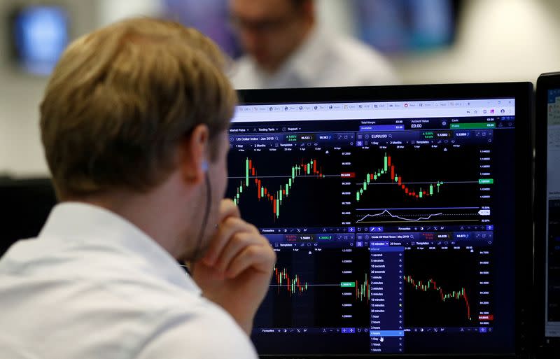 FILE PHOTO: A financial trader works at their desk at CMC Markets in the City of London